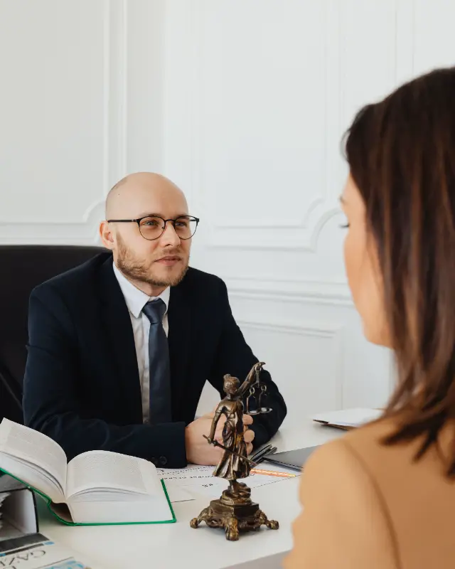 Un avocat écoute une cliente assise face à lui, à son bureau