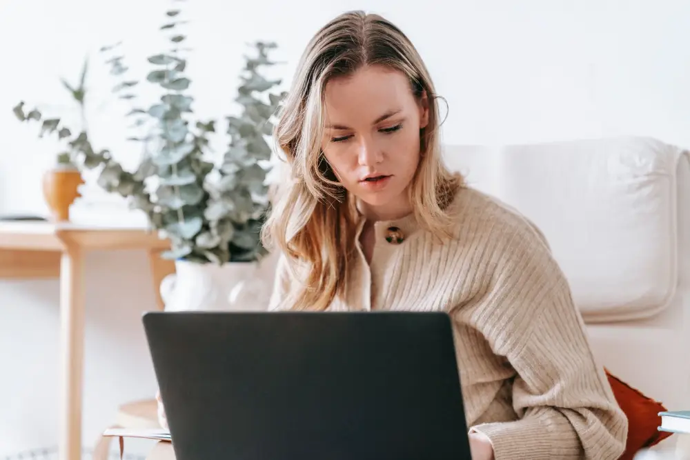 Une indépendante concentrée travaille sur son ordinateur depuis chez elle