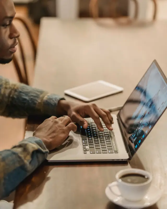 Un freelance tape sur son ordinateur portable, un café posé à côté