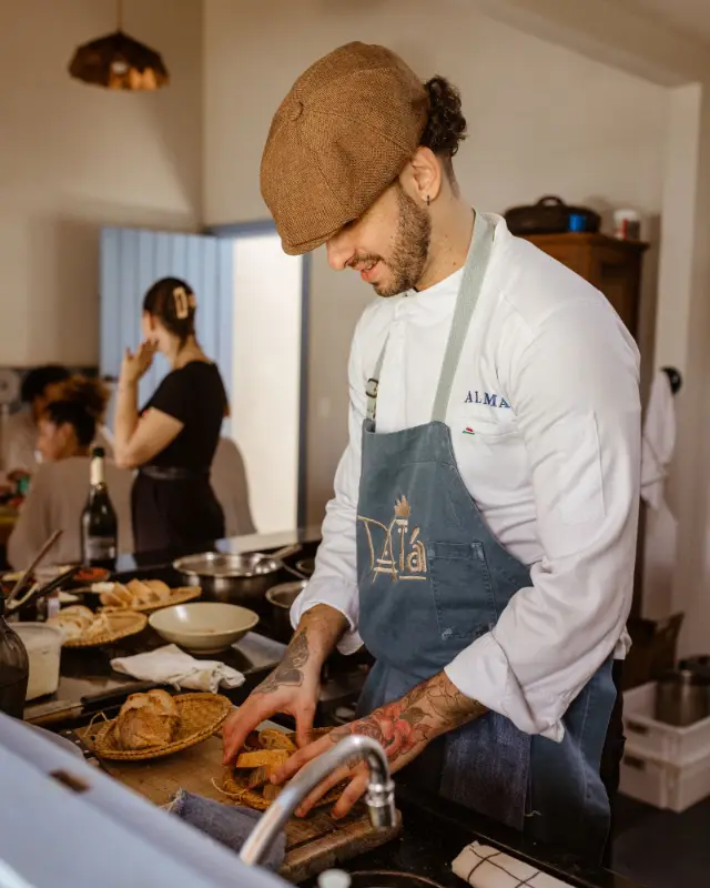 Un cuisinier souriant prépare des plats sur le plan de travail d’une cuisine ouverte